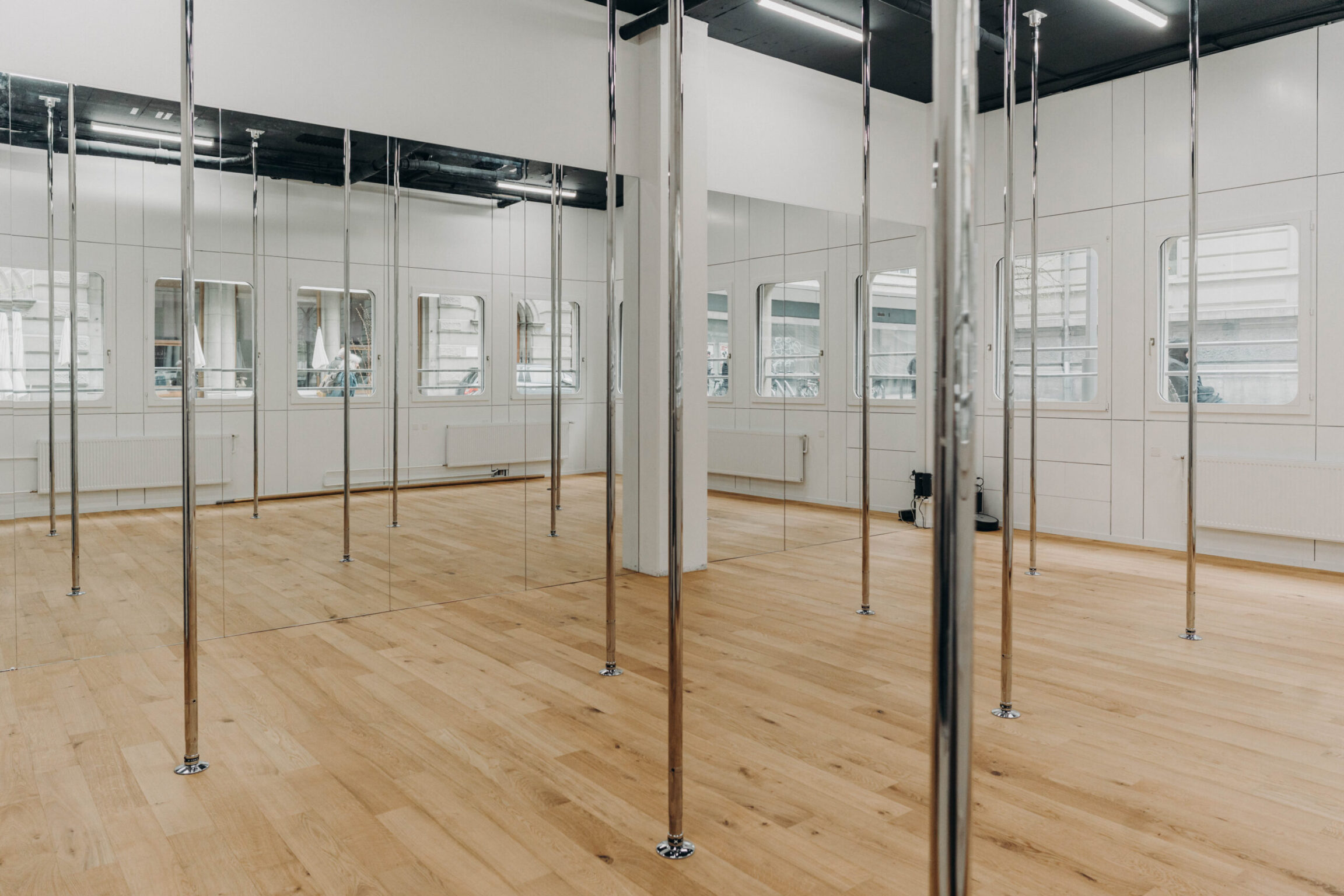 Salle de pole dance avec barres et miroirs au studio PoleMovement de Fribourg